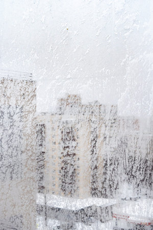 frosty window glass and cityscape on overcast winter day (focus on the surface on windowpane)の写真素材
