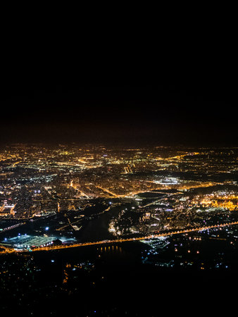 aerial view of black sky and illuminated suburbs of Moscow city at night from porthole while flying by planeの写真素材