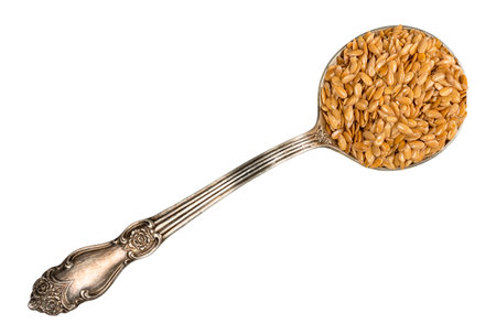 top view of golden flax seeds in silver tablespoon cutout on white backgroundの写真素材