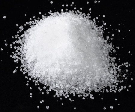 pile of fructose crystalline sugar closeup on black plate