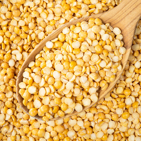 top view of dried split yellow peas in wooden spoon closeup