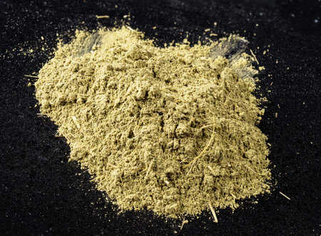 handful of powder of stevia rebaudiana herb (natural sugar substitute) closeup on black plate