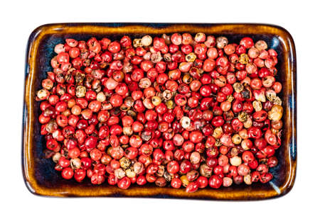 top view of pink peppercorns (Baie rose) in ceramic bowl cutout on white backgroundの写真素材