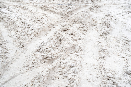tire tracks on snow covered surface of city road on winter day
