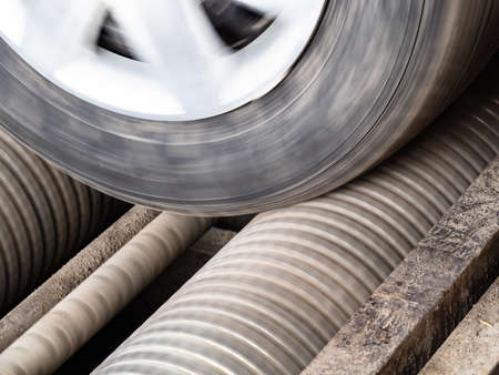 rotating car wheel on roller brake tester closeup on MOT inspection lane in car workshopの写真素材