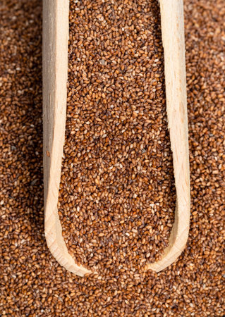 top view of wood scoop on pile of wholegrain teff seeds closeup