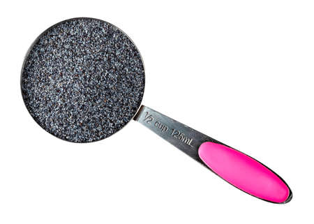 top view of poppy seeds in measuring cup cutout on white backgroundの写真素材