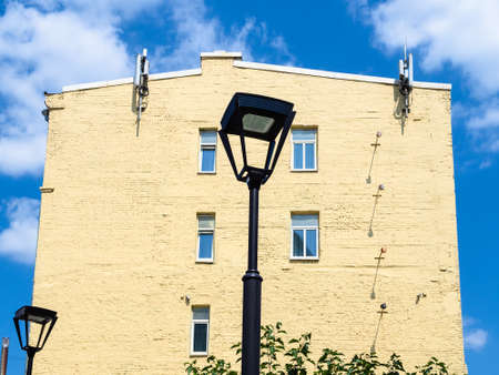 street lantern, yellow painted wall of old brick house and blue sky with white clouds in Moscow city on sunny summer dayの写真素材