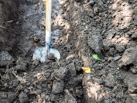 digging a ditch with shovel on summer day