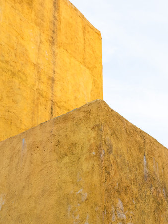 rough plastered painted yellow wall and blue sky in autumn twilight