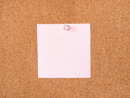 pink blank note paper pinned to cork board closeup