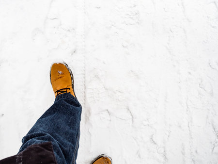 top view of yellow leather boot on snow-covered path on overcast winter day