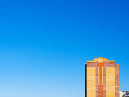 city background - blue sky and orange wall of urban brick house on sunny summer morningの写真素材