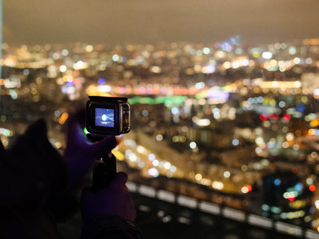 visitor films night city on mobile camera from the observation deckの写真素材