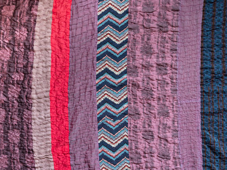 textile background - hand stitched patchwork cloth from various fabric stripes