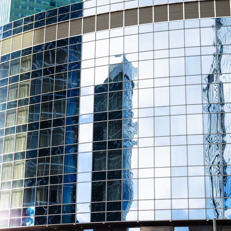 blue cloudy sky and towers are reflected in glass wall of skyscraper on cloudy day in Moscow city...