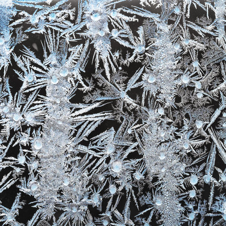 textured frost pattern on window glass closeup on cold winter day
