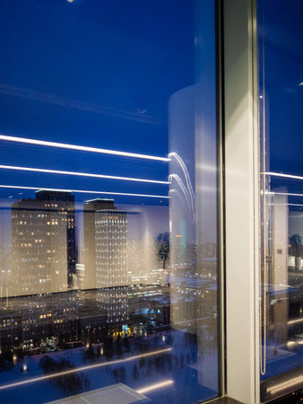 view of apartment buildings and reflection of office lamps through window glass of high-rise...