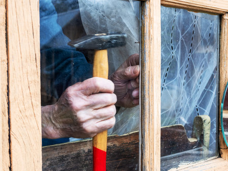 fixing window glass in wooden frame with nail in rural house close upの写真素材