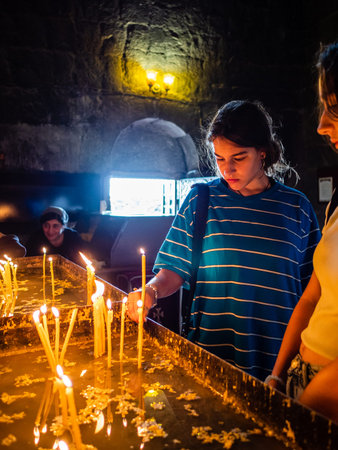 Sevan, Armenia - August 25, 2023: tourist lights candle in Surp Arakelots church in Sevanavank...