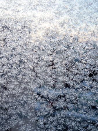 frosty pattern on home window glass close up on cold winter duskの写真素材