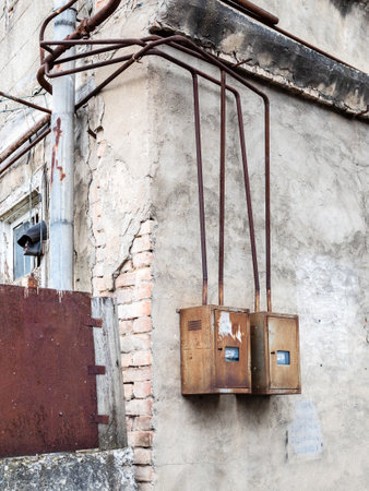 electricity meters in rusty cases on wall of shabby house on street in Tbilisi city, Georgia on summer dayの写真素材