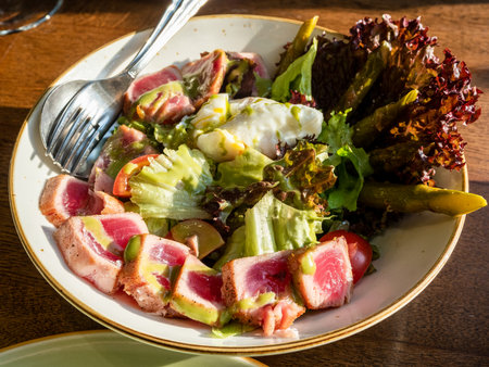 served tuna and lettuce salad in bowl illuminated by sun light on tableの写真素材