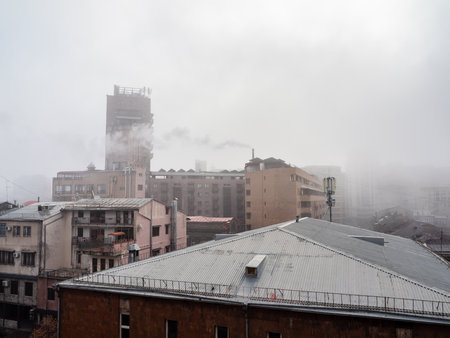smoke, smog and fog over rooftops in Yerevan city in winter morningの写真素材