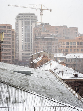 snow-covered roofs of urban houses in snowfall on winter day in Yerevan city, Armeniaの写真素材