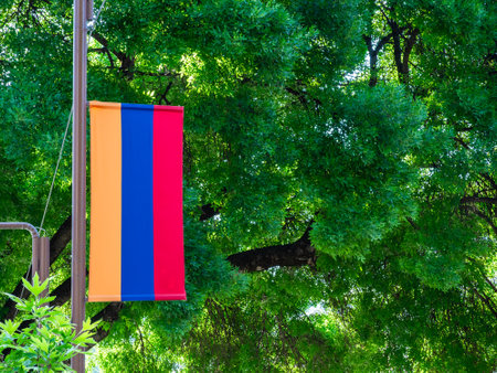 armenian flag and lush green foliage in background in sunny spring morning in Kapan town, in Syunik Province of Armeniaの写真素材