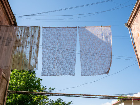 tulle curtains dry on clothesline between city houses in Kapan town, in Syunik Province of Armenia in sunny spring morningの写真素材