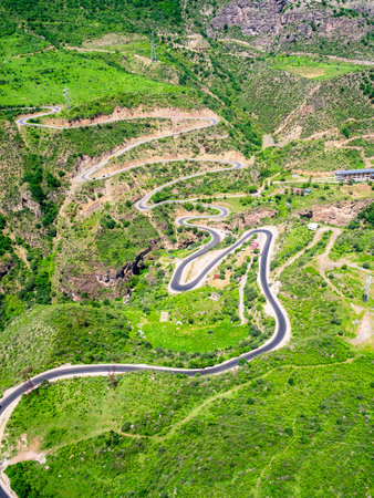 aerial view of Devil's Bridge on serpentine road in mountain Vorotan River Gorge between villages of Tatev and Halidzor from Wings of Tatev funicular on sunny May day in Syunik Province of Armeniaの写真素材