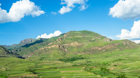 panoramic view of green field and gardens on slope of mountain in Syunik province of Armenia on sunny May dayの写真素材