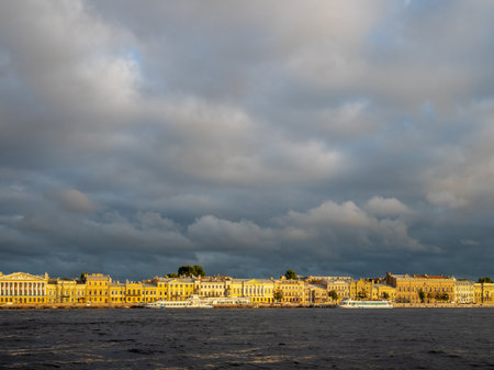 gray clouds over English Embankment of Great Neva river in Saint Petersburg city, Russia lit by setting sun in summer eveningの写真素材