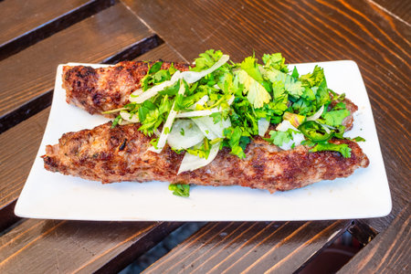 Georgian meat kebab on white plate on wooden table in outdoor local cafe in Borjomi town, Georgia on...