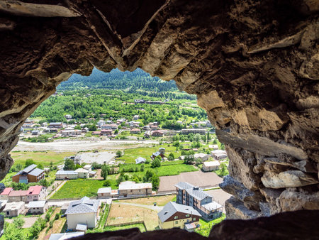 above view of Mestia townlet and Mulkhra river from arch window in svan tower in in Samegrelo-Zemo Svaneti province of Georgia on sunny summer dayの写真素材