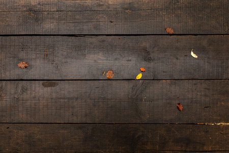 Autumn concept. Dark wet wooden table with some brown and yellow leaves on top. Texture for...