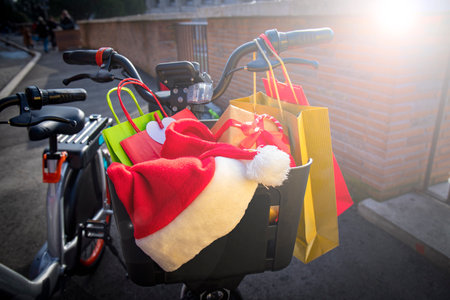 Christmas shopping time. Bicycle basket full of Christmas gifts and colorful shopper bags. Santa Claus hat resting on top of the presents.の写真素材