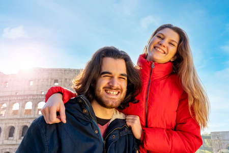 Young couple traveling to Rome. The couple smiles and takes a selfie in front of the Colosseum.の写真素材