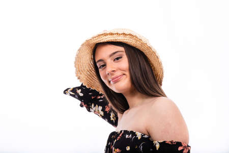 Portrait of beautiful smiling girl with long hair. The young woman is wearing a black floral dress and a hat.の写真素材
