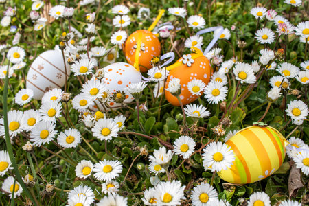 Happy Easter! Easter decorated eggs. Multicolored Easter eggs among daisies in the garden.