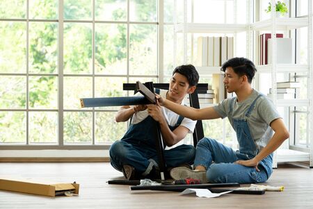 Two carpenters discussed the type of bench being assembled. Handyman installing wooden bench in new house. House renovation service. Morning work atmosphere in the living room.の写真素材