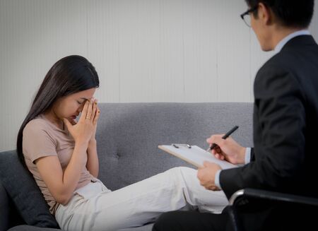 Sad woman with depression having consultation with psychiatrist in hospital mental health service centerの写真素材