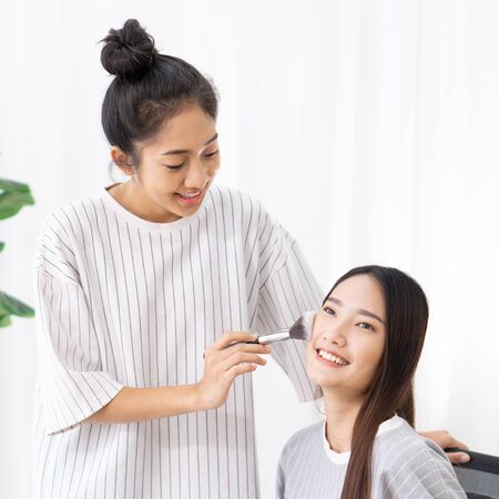 Roommates have fun learning to make-up for asian friends.の写真素材