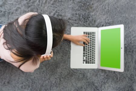 Teen wearing headphones using  laptop computer with green screen relax in living room, enjoy leisure weekend at home. Stress free concept. Top Viewの写真素材