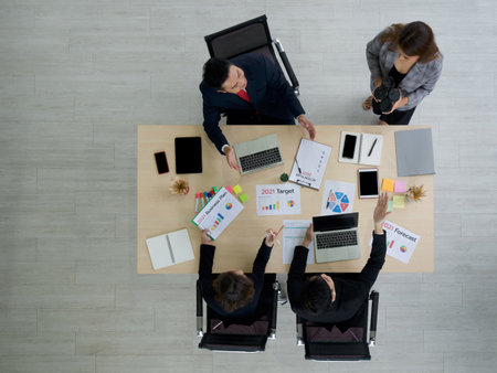 Asian manager in a suit and team examine the documents on the desk while the secretary brings the coffee.の写真素材