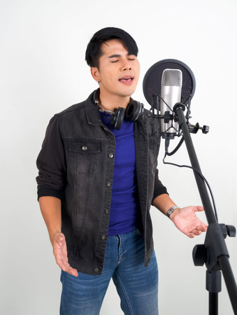 Young asian man with headphones  singing with microphone. Portrait on white background with studio light.の写真素材