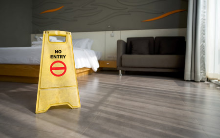 A yellow NO ENTRY sign place on the floor in hotel room. While cleaning