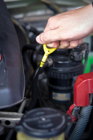 Closeup hand pulling the engine oil dipstick. Mechanic checking level motor oil in a car with open...