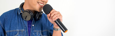 Closeup musician's hand holding microphone. Young asian man singing on white background.